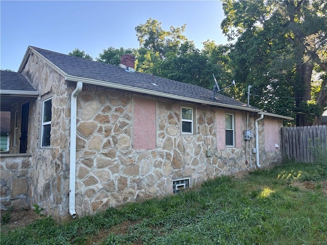 6941 Spruce Ave, Kansas City, MO 64132 - view of side of property with stone siding, a chimney, and roof with shingles