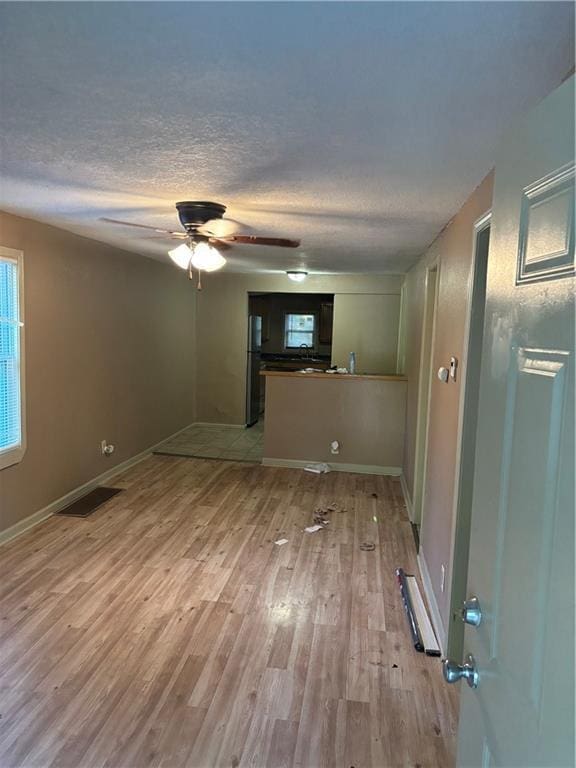 6941 Spruce Ave, Kansas City, MO 64132 - unfurnished living room featuring a textured ceiling, light wood-type flooring, and a ceiling fan