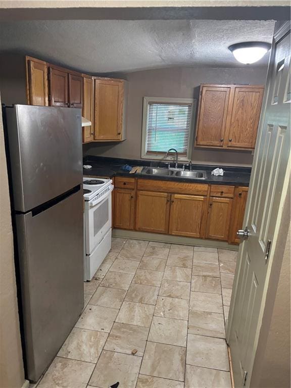 6941 Spruce Ave, Kansas City, MO 64132 - kitchen featuring freestanding refrigerator, white electric stove, dark countertops, brown cabinetry, and vaulted ceiling