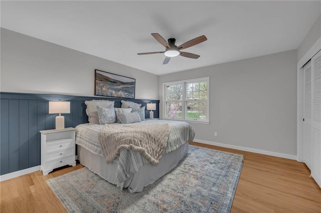 bedroom featuring baseboards, a closet, ceiling fan, and wood finished floors
