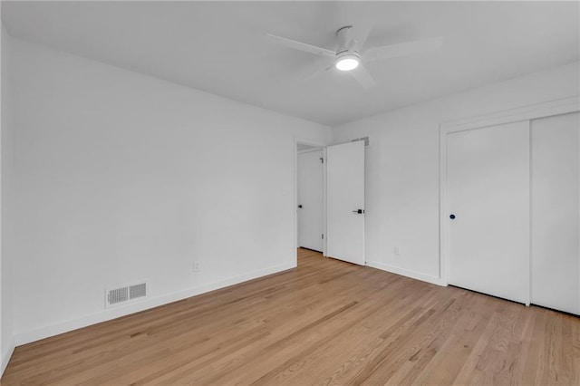 unfurnished bedroom featuring wood finished floors, a closet, baseboards, and visible vents