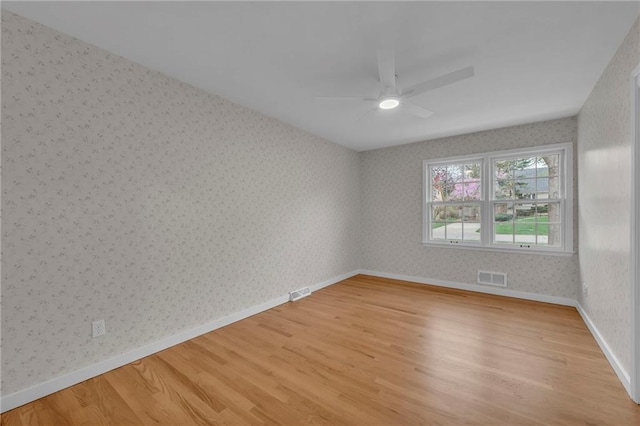 empty room featuring baseboards, wallpapered walls, light wood-style floors, ceiling fan, and visible vents