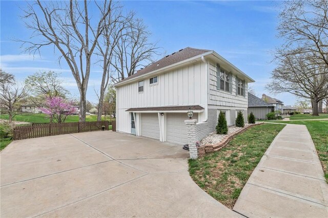 view of side of home featuring a lawn, fence, a garage, and roof with shingles
