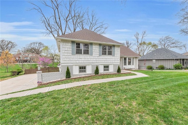view of front facade featuring fence, concrete driveway, and a front yard