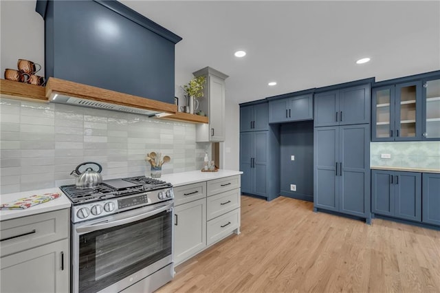 kitchen with light wood-type flooring, ventilation hood, stainless steel gas stove, and light countertops