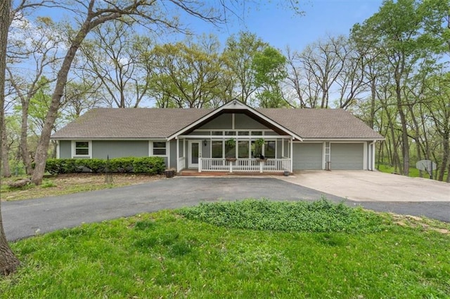 view of front facade featuring driveway, an attached garage, and covered porch