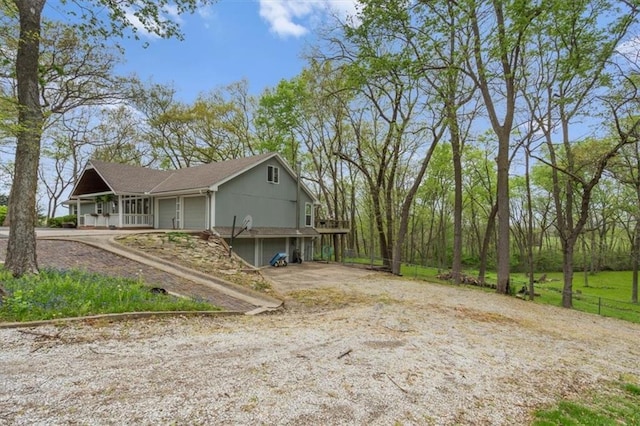 view of home's exterior with driveway, fence, a porch, and a garage