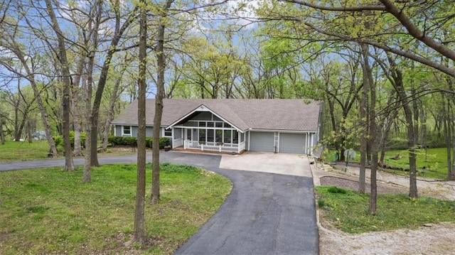 view of front of house with covered porch, a front yard, driveway, and an attached garage