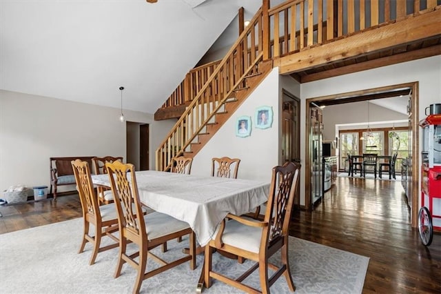 dining room with stairway, wood finished floors, and high vaulted ceiling