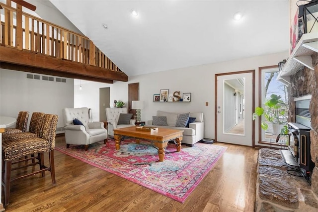 living room featuring high vaulted ceiling, wood finished floors, and a wood stove