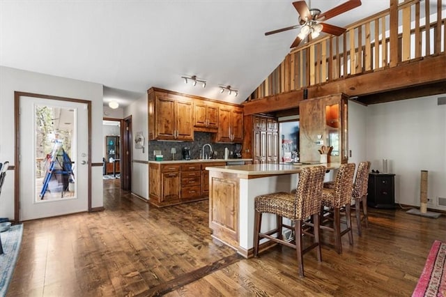 kitchen featuring a sink, ceiling fan, light countertops, dark wood-type flooring, and brown cabinetry