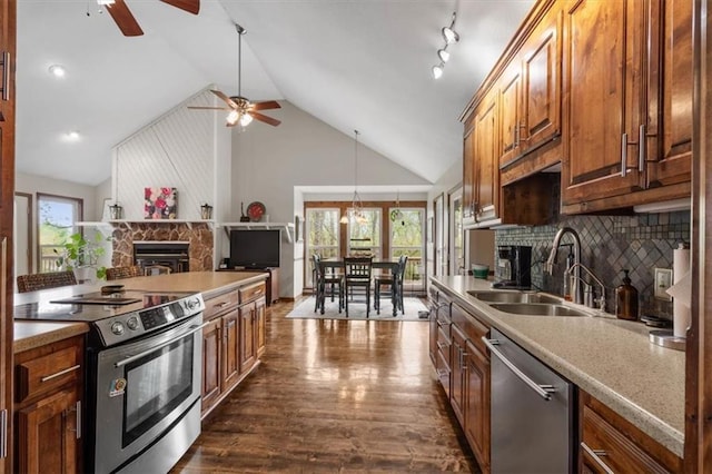 kitchen with a sink, stainless steel appliances, dark wood-style flooring, a fireplace, and a ceiling fan