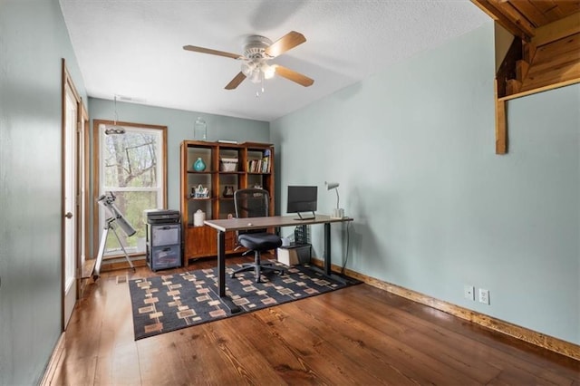 home office with baseboards, wood finished floors, a ceiling fan, and a textured ceiling
