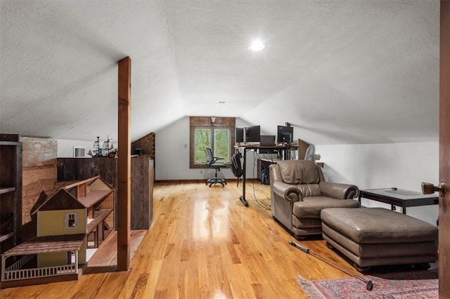 office space featuring lofted ceiling, a textured ceiling, wood finished floors, and visible vents