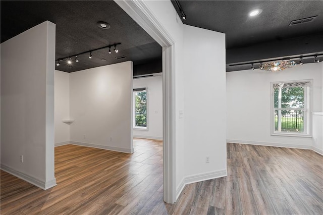 11273 S Lakecrest Dr, Olathe, KS 66061 - empty room with rail lighting, wood finished floors, plenty of natural light, a textured ceiling, and baseboards