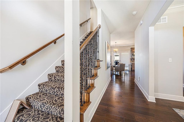 stairway featuring wood finished floors, visible vents, and baseboards