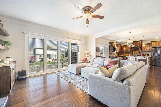 living room with visible vents, ornamental molding, dark wood-type flooring, a textured ceiling, and ceiling fan with notable chandelier