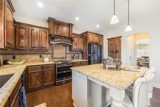 kitchen with dark wood-style floors, arched walkways, a kitchen island, double oven range, and refrigerator with ice dispenser