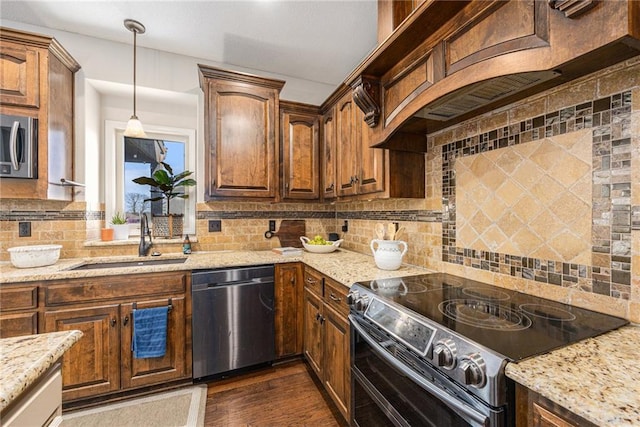 kitchen with stainless steel appliances, dark wood-style floors, a sink, backsplash, and light stone countertops