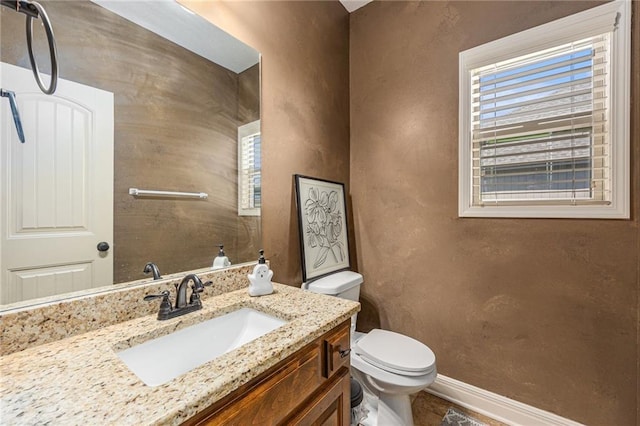 bathroom featuring toilet, vanity, and baseboards