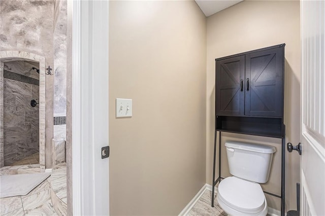 full bath with a tile shower, toilet, and baseboards