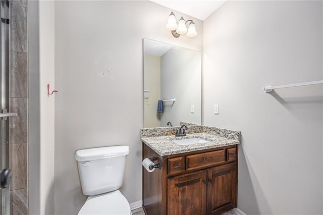 bathroom with tiled shower, baseboards, vanity, and toilet