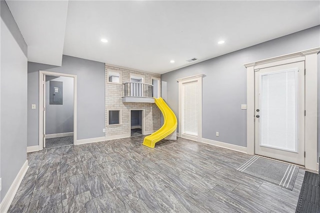 rec room featuring marble finish floor, visible vents, electric panel, baseboards, and a brick fireplace