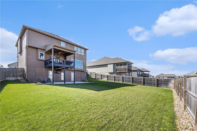 back of house featuring a fenced backyard, a balcony, and a yard