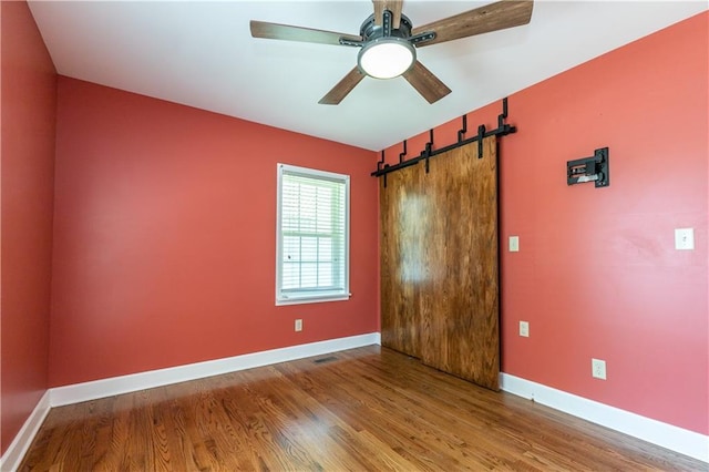 1306 W 29th St S, Independence, MO 64052 - unfurnished bedroom featuring wood finished floors, a barn door, and a ceiling fan