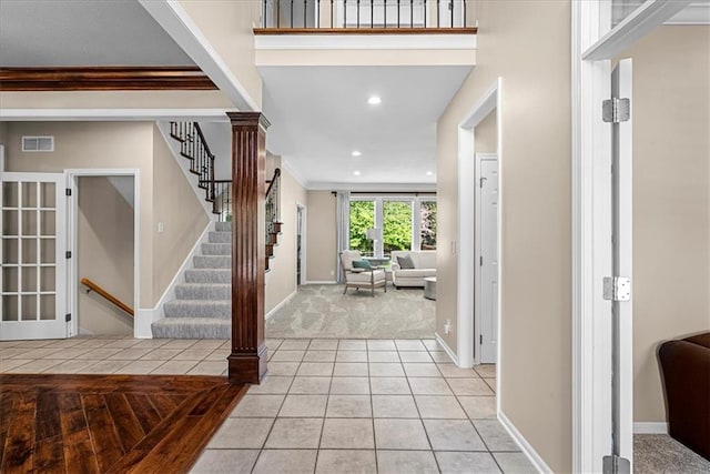 entrance foyer featuring stairs, light tile patterned floors, light carpet, baseboards, and visible vents