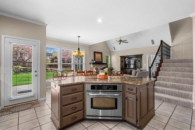 kitchen featuring open floor plan, ceiling fan with notable chandelier, oven, and light tile patterned floors