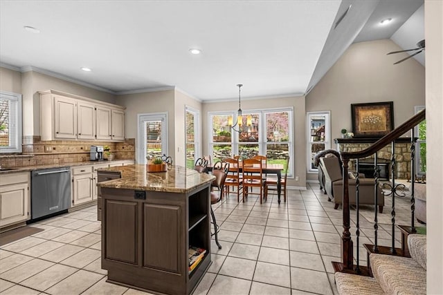 kitchen featuring a center island, stainless steel dishwasher, backsplash, light stone counters, and light tile patterned floors