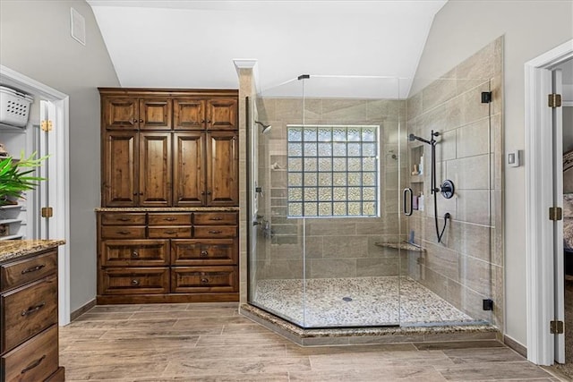 full bathroom featuring vaulted ceiling, wood finished floors, and a shower stall
