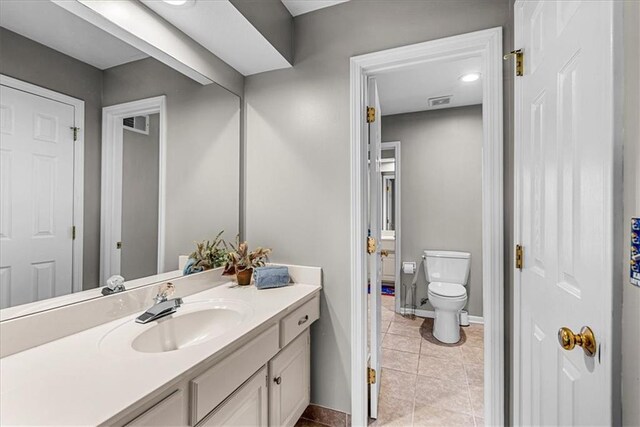 bathroom with tile patterned flooring, visible vents, toilet, vanity, and baseboards