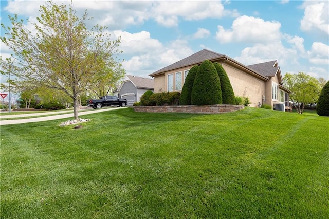 view of side of property with central AC unit, a lawn, driveway, a garage, and stucco siding