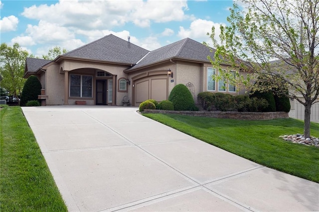 french country inspired facade with concrete driveway, an attached garage, a shingled roof, a front yard, and stucco siding