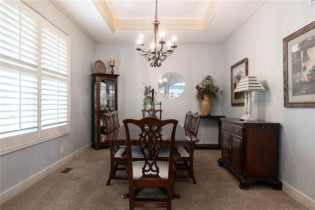 dining area with light carpet, ornamental molding, a tray ceiling, and a chandelier