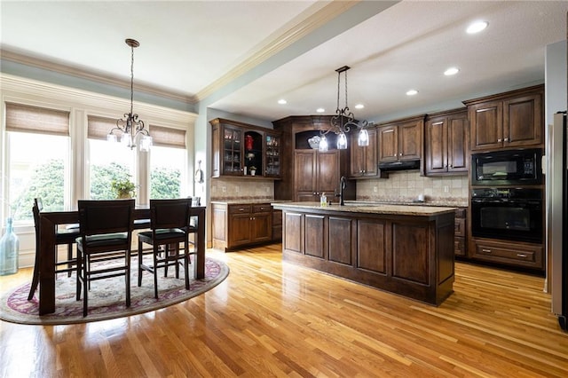 kitchen featuring an inviting chandelier, a sink, under cabinet range hood, and black appliances