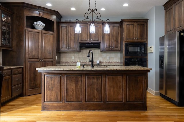kitchen featuring a sink, light wood-type flooring, dark brown cabinets, under cabinet range hood, and black appliances