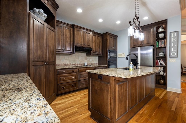 kitchen with under cabinet range hood, open shelves, a sink, light wood-type flooring, and black appliances