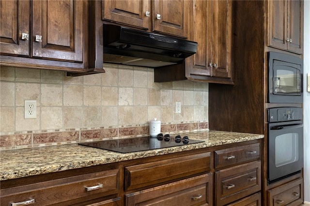 kitchen with light stone counters, under cabinet range hood, dark brown cabinetry, decorative backsplash, and black appliances