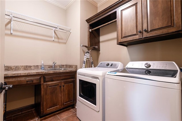 clothes washing area featuring washing machine and clothes dryer, a sink, crown molding, cabinet space, and dark tile patterned floors