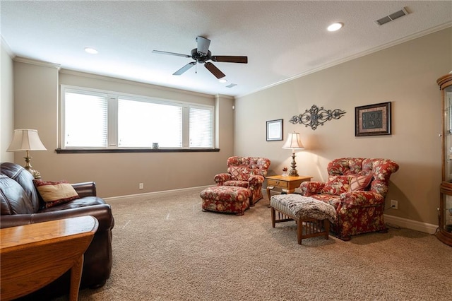 living room featuring visible vents, a ceiling fan, ornamental molding, carpet floors, and baseboards