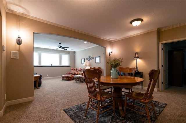 carpeted dining room featuring ceiling fan, baseboards, ornamental molding, and a textured ceiling