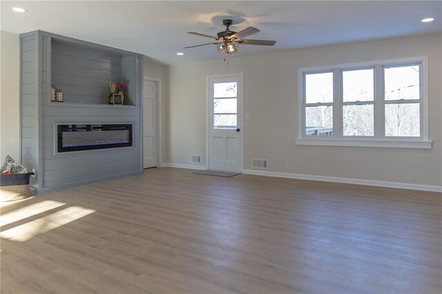 909 Bell Dr, Excelsior Springs, MO 64024 - unfurnished living room with a glass covered fireplace, wood finished floors, baseboards, recessed lighting, and ceiling fan