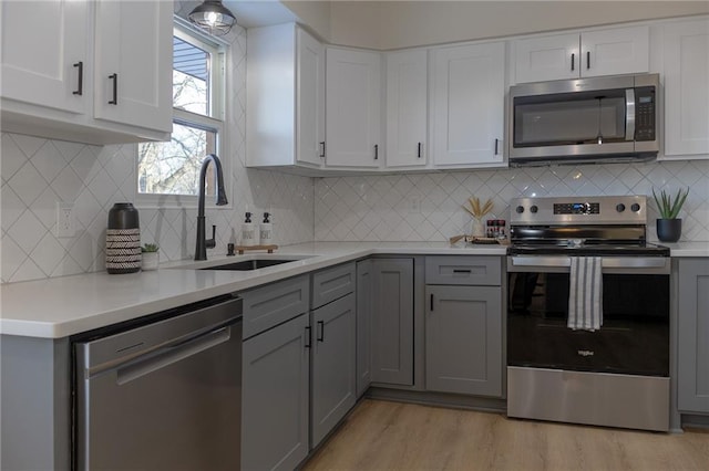 909 Bell Dr, Excelsior Springs, MO 64024 - kitchen featuring stainless steel appliances, a sink, gray cabinets, light countertops, and light wood-type flooring