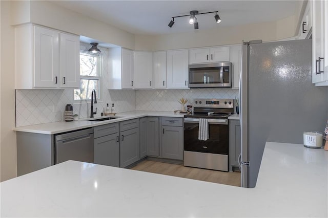 909 Bell Dr, Excelsior Springs, MO 64024 - kitchen featuring stainless steel appliances, a sink, light wood-style flooring, light countertops, and backsplash