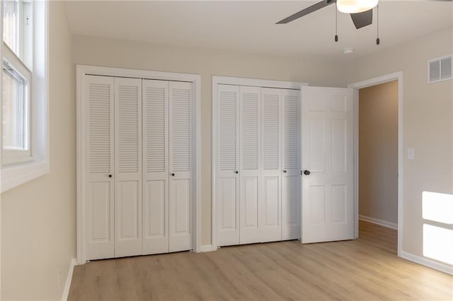 909 Bell Dr, Excelsior Springs, MO 64024 - unfurnished bedroom featuring multiple closets, light wood-style flooring, baseboards, and ceiling fan