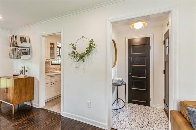 hallway with wood-type flooring, crown molding, and baseboards