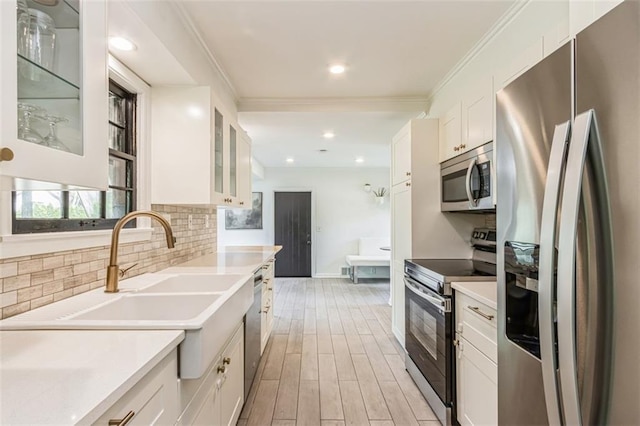 kitchen featuring crown molding, decorative backsplash, white cabinets, and stainless steel appliances